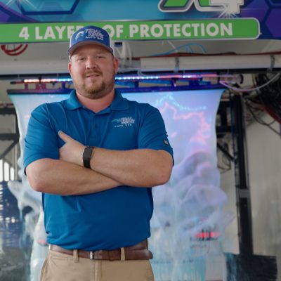 Confident Tidal Wave Auto Spa team member standing in an express car wash tunnel