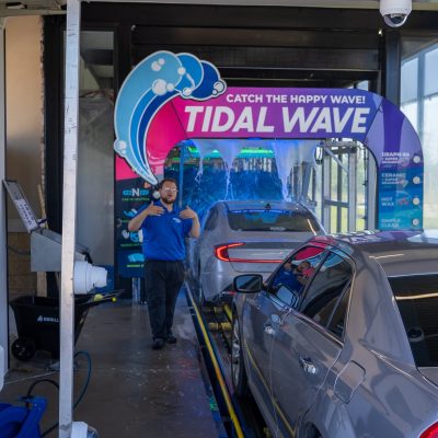 Confident Tidal Wave Auto Spa team member standing in an express car wash tunnel