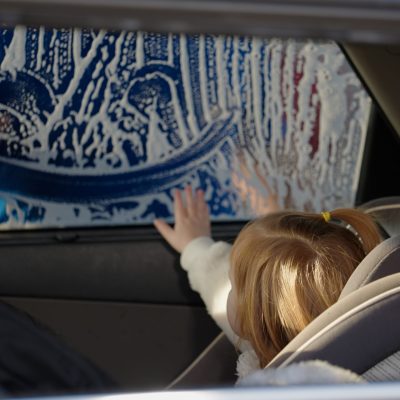 Child enjoying Tidal Wave Auto Spa car wash from inside family vehicle.