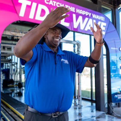 Confident Tidal Wave Auto Spa team member standing in an express car wash tunnel