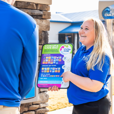 Confident Tidal Wave Auto Spa team member helping customer choose wash