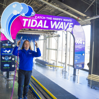 Confident Tidal Wave Auto Spa team member standing in an express car wash tunnel